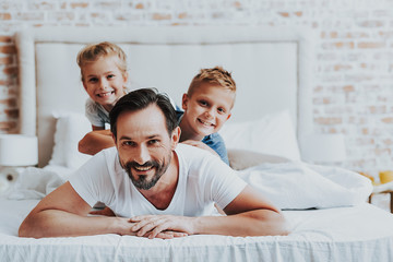 Happy father laying on bed with two kids