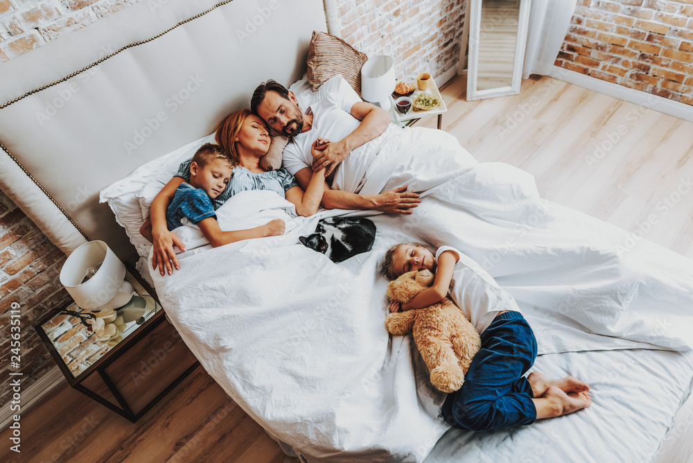 Wall mural top view of family sleeping together in bed