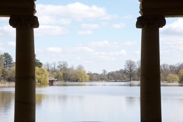 A beautiful tranquil English lake on a spring day, seen framed between silhouetted columns / pillars