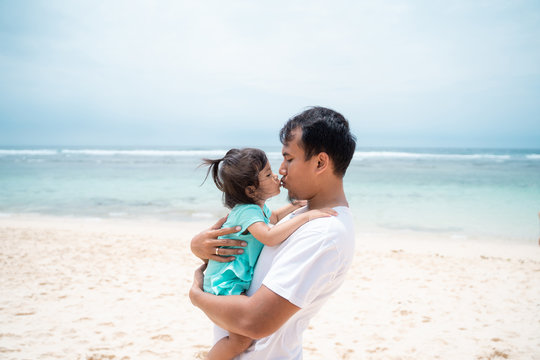 father and his daughter kissing each other on the beach 