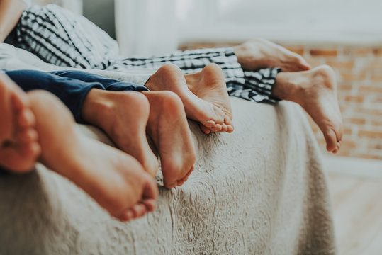 Close Up Family Four Pairs Of Feet In Bed