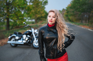 Fototapeta na wymiar A stylish biker woman posing with a motorcycle on the road. 