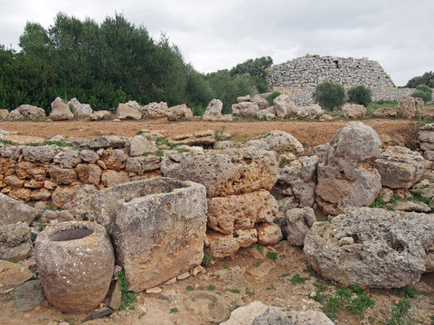 ancient stone walls and ancient objects in trepuco minorca with talayot and enclosure in the distance
