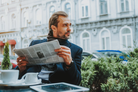Relaxed man is reading newspaper in cafe