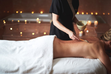 Therapist applying healthy spa mud to young lady