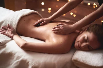 Photo sur Plexiglas Salon de massage Dame souriante se faisant masser avec des pierres chaudes