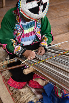Pisac, Cusco, Peru - Oct 20, 2018: Quechua woman demonstrating traditional weaving techniques at a market in the Sacred Valley.