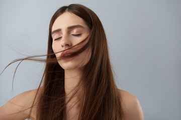 Charming girl with beautiful long hair posing against light blue background