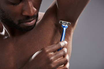 Close up of afro American man using his razor for shaving