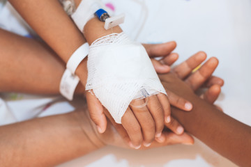 Mother and daughter holding hand who have IV solution bandaged together with love and care in the hospital