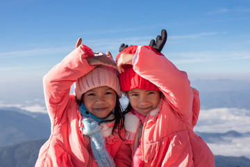 Two cute asian child girls wearing sweater and warm hat making heart together with love at the...