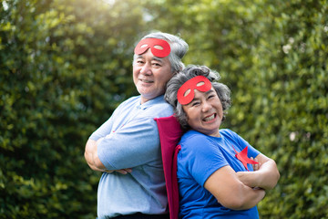 Senior couple in Superhero costume lauging with arms crossed.