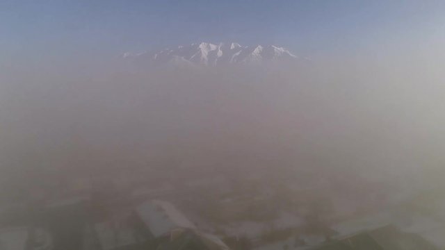 Flying through thick fog rising up and out into clear air viewing snow covered mountains in Utah.