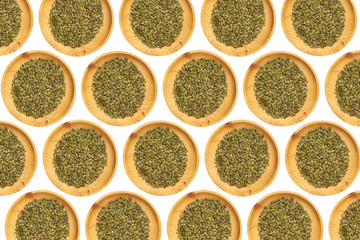 Peeled pumpkin seeds   in a wooden pine plate on a white isolated background. Row of bowls with  pumpkin seeds  nuts, top view. Peeled pumpkin seeds    pattern