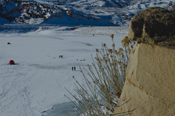 Looking down from the rock ledge at the frozen lake and the people ice fishing 