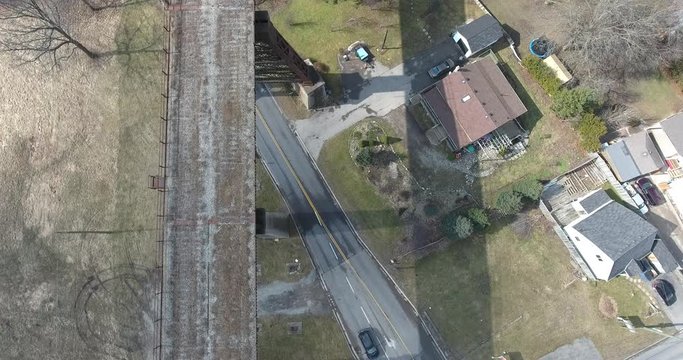 Abandoned Bridge Over Road By Houses Aerial View With Car Driving By