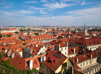 Fototapeta na wymiar Prague on a sunny summer day. Top view of the red roofs of houses, St. Vitus Cathedral.