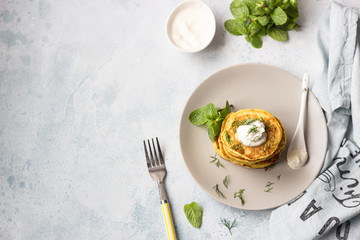 Zucchini fritters served with fresh herbs and yogurt dressing. Vegetarian zucchini pancakes. Copy space.
