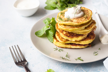 Zucchini fritters served with fresh herbs and yogurt dressing. Vegetarian zucchini pancakes. Copy space.