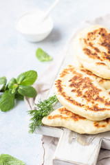 Frying pan baked flat bread with fresh herbs and yogurt dressing. Khychiny or qutab - traditional caucasian or Azerbaijani flatbread.