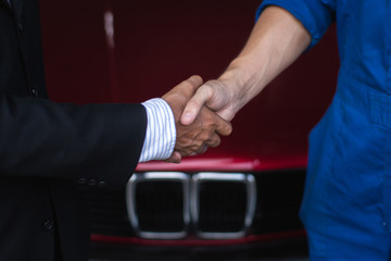 auto service, repair, maintenance concept mechanic with clipboard and car businessman owner shaking hands at car shop