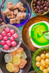 Tea break with a delicious honey cake decorated in the form of a green apple and a variety of multi-colored small candies. Copper and clay plates in a composition with jugs. Arab concept