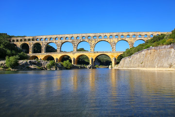 Fototapeta na wymiar Aqueduct Pont du Gard reflected in Gardon River, southern France