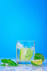 cocktail with lime and fresh mint in glass on a blue background
