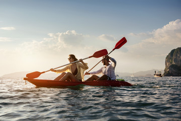 Happy coulple walks by sea kayak or canoe at sunset bay. Kayaking or canoeing concept with people