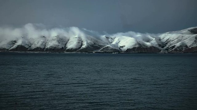 4K Time Lapse of Winter Lake and snow covered mountains with mystery fog clouds at night footage for different projects. Shooted in Armenia lake (Sevan).