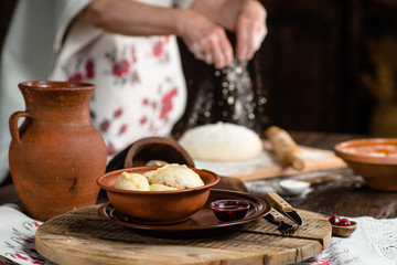 Obraz na płótnie Canvas Ukrainian dumplings on a wooden board on the background of the hands of a baker