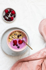 Bowl of oat granola with yogurt, fresh raspberries, cranberries