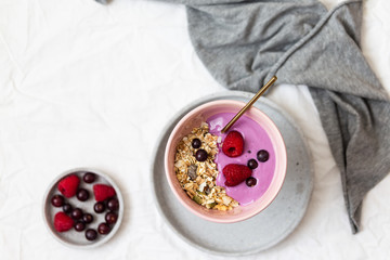 Bowl of oat granola with yogurt, fresh raspberries, cranberries