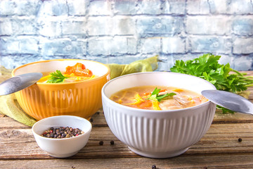 Homemade chicken soup with noodles and vegetables in metal pan on wooden table