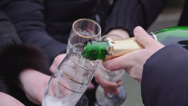 Someone opens the champagne and pours into glasses