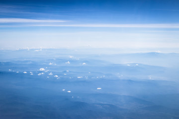 clouds and blue sky with mountain background, view from window of airplane