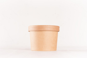 Blank disposable brown paper box for takeaway food - soup, salad, ice cream on white wood shelf closeup, mockup food  packaging for cafe, bar and restaurant.