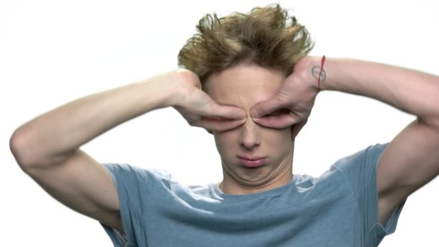Teen boy making funny face grimace. Teenage guy with crazy hoar having fun over white background.
