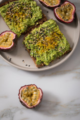 Avocado Kurkuma Vollkorn Sonnenblumenkern Brot und Maracuja zum Frühstück auf Marmor Hintergrund