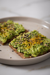 Avocado Kurkuma Sesam Vollkorn Sonnenblumenkern Brot als Snack oder Frühstück auf Marmor Hintergrund
