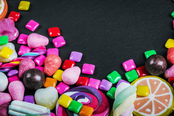 candy, gum, lollipops, marmalade and other sweets on black background
