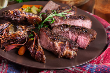 Slices of beef steak served with baked artichoke