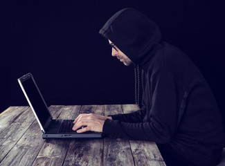 hacker in black hoody with laptop