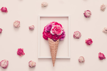 Conceptual flower gift composition. Carnation in cream cone arranged in frame. Rose heads on ivory background.