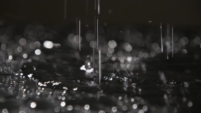 Abstract splashes of rainy water covering cave soil with strange dots in slo-mo   