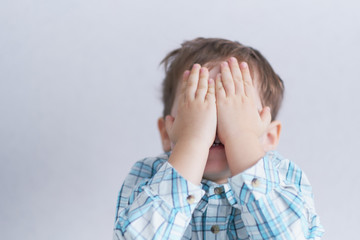 funny boy three years old hid his face in his hands. childhood fears.