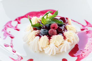 Meringue cake with berries on a white plate