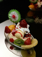 Bandeja con un  Banana Split, con piña, melocotón,  fresas naturales, plátano, dos bolas de helado, nata montada y un adorno de papel 