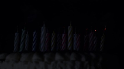 Anniversary cake burning candles in dark 