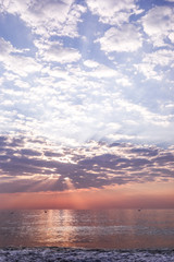 View of seascape with beautiful sky with clouds and sunbeams on sunrise.